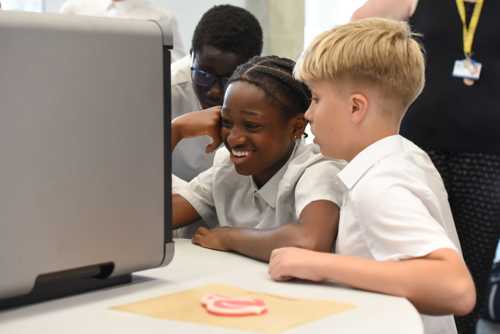 Secondary school students watching a 3D food printer in action.